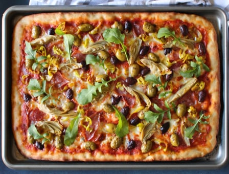 Sheet pan pizza served on a sheet pan and topped with lots of Mezzetta products
