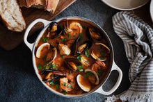 Load image into Gallery viewer, A large pot of cioppino with a side of bread
