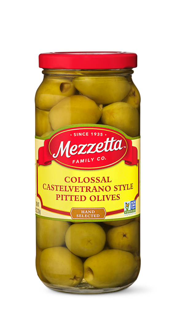 A glass jar filled with Mezzetta brand Colossal Castelvetrano Style Pitted Olives. The jar showcases the large, green olives through the glass.