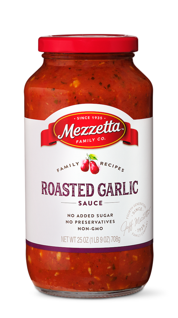 A clear glass jar of Mezzeta Family Co. Roasted Garlic Sauce against a black background. The sauce is red with visible herbs and spices.