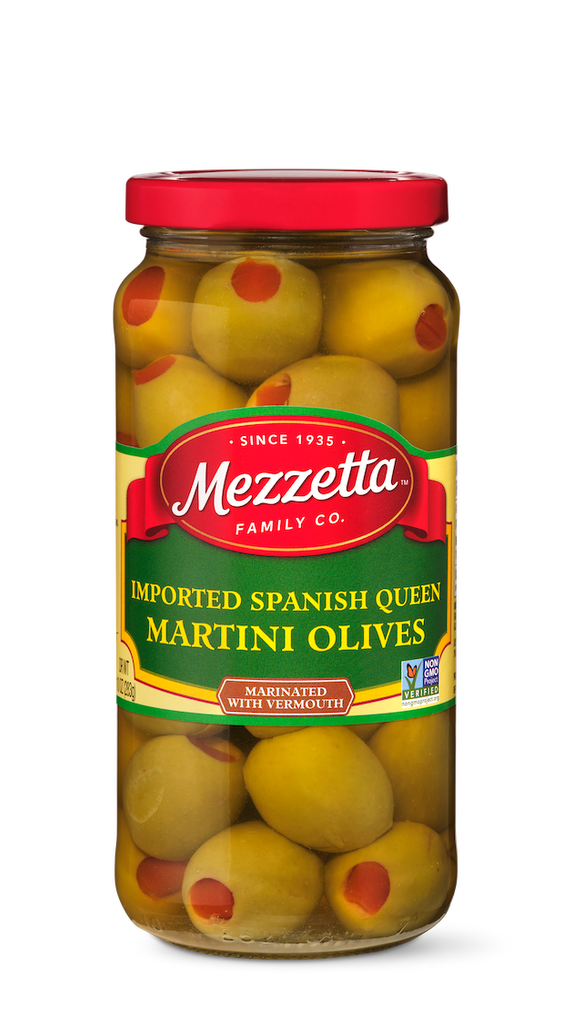 A glass jar filled with Mezzetta Spanish Queen martini olives, each one garnished with a bright red pimento.