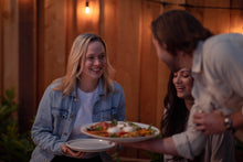 Load image into Gallery viewer, Man serving a woman a plate of burrata and tomatoes
