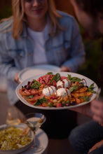 Load image into Gallery viewer, A woman being served a burrata and tomato plate
