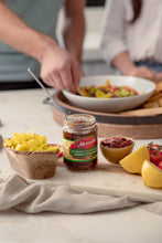 Load image into Gallery viewer, Man adds Mezzetta® Julienne Cut Sun-Ripened Dried Tomatoes to a salad with fresh ingredients.