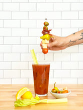 Load image into Gallery viewer, Hands placing a antipasto skewer on a bloody mary
