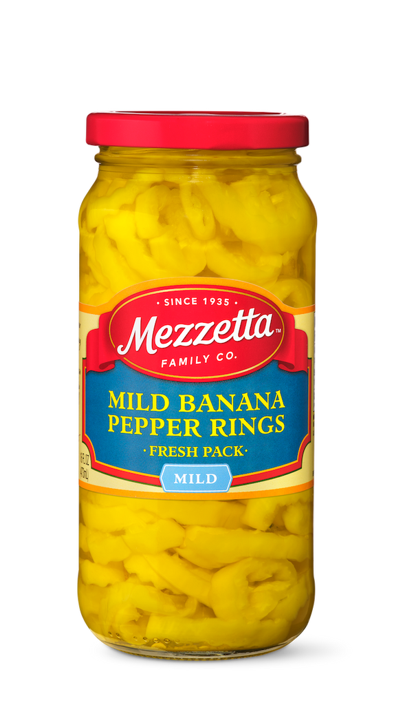 A glass jar displays sliced mild banana pepper rings packed in water. The Mezzetta brand label highlights the product's mild flavor and fresh pack.
