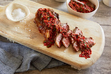 Load image into Gallery viewer, A Seared Steak with Pepper Chimichurri served with salt on a wooden platter
