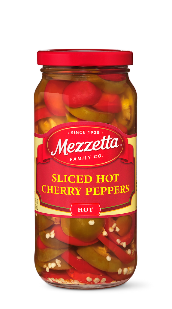 A jar of Mezzetta sliced hot cherry peppers sits against a black background.