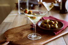 Load image into Gallery viewer, A classic dirty martini with three olives served on a wooden board with a side of olives
