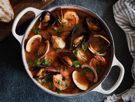 A large pot of cioppino with clams and shrimp