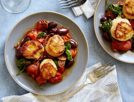 Two plates of scallops with Kalamata olives and tomatoes