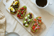 Load image into Gallery viewer, Four pieces of avocado toast with assorted Mezzetta products on top
