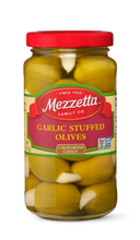 Load image into Gallery viewer, A glass jar filled with Mezzetta Garlic Stuffed Olives, each olive bursting with a plump garlic clove. 

