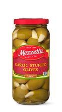 Load image into Gallery viewer, A glass jar filled with Mezzetta Garlic Stuffed Olives. The jar sits with a red lid on a white background. 

