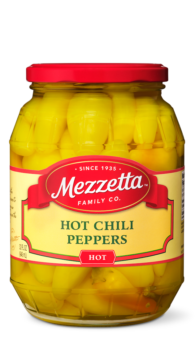 A glass jar brims with Mezzetta brand pickled hot chili peppers, ready to add a fiery kick to any dish. 
