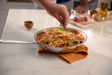 Load image into Gallery viewer, Hand sprinkling basil on a pan of pasta made with Mezzetta Marinara
