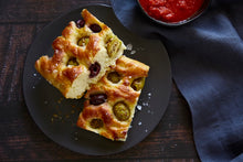 Load image into Gallery viewer, Two pieces of Mediterranean Za&#39;atar Olive Focaccia bread on a black plate with Mezzetta Marinara Sauce for dipping
