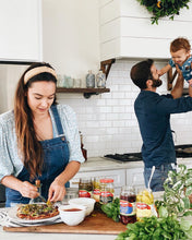 Load image into Gallery viewer, Family making homemade pizza with Mezzetta products while playing with a baby
