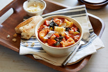Load image into Gallery viewer, A bowl of Tuscan Ribollita soup on a wooden plater with a side of bread

