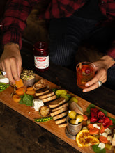 Load image into Gallery viewer, Hands enjoying a charcuterie board with Mezzetta Garlic Stuffed Olive and a cocktail with Mezzetta Maraschino Cherries
