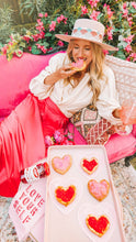 Load image into Gallery viewer, Woman eating a heart shaped cookie made with Mezzetta Maraschino Cherries
